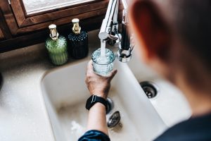 088350fb-man-filling-a-glass-of-filtered-water-right-from-the-tap-in-the-kitchen-1368715188