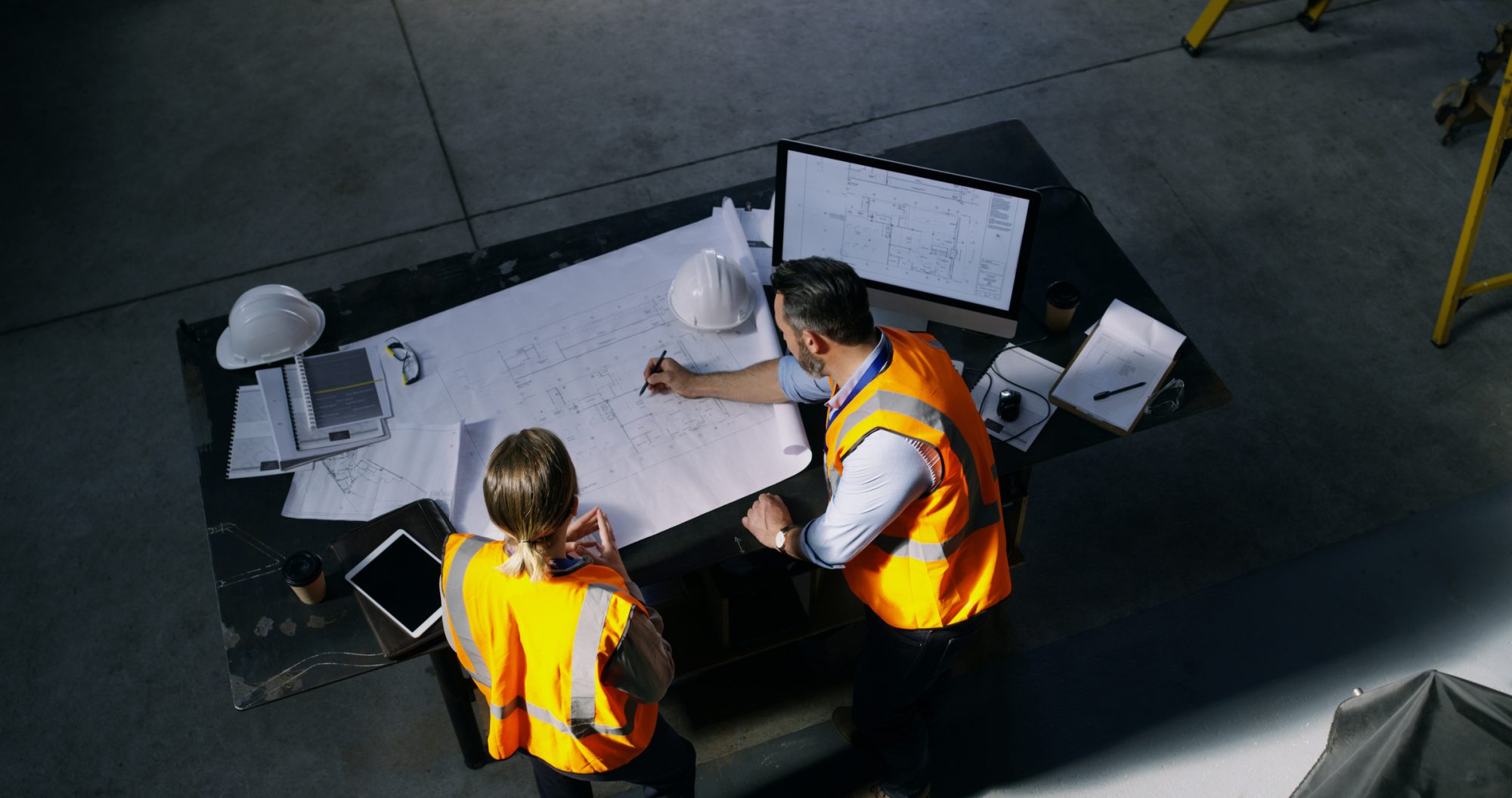316527a9-engineering-design-high-angle-shot-of-two-engineers-going-over-a-blueprint-1164943425