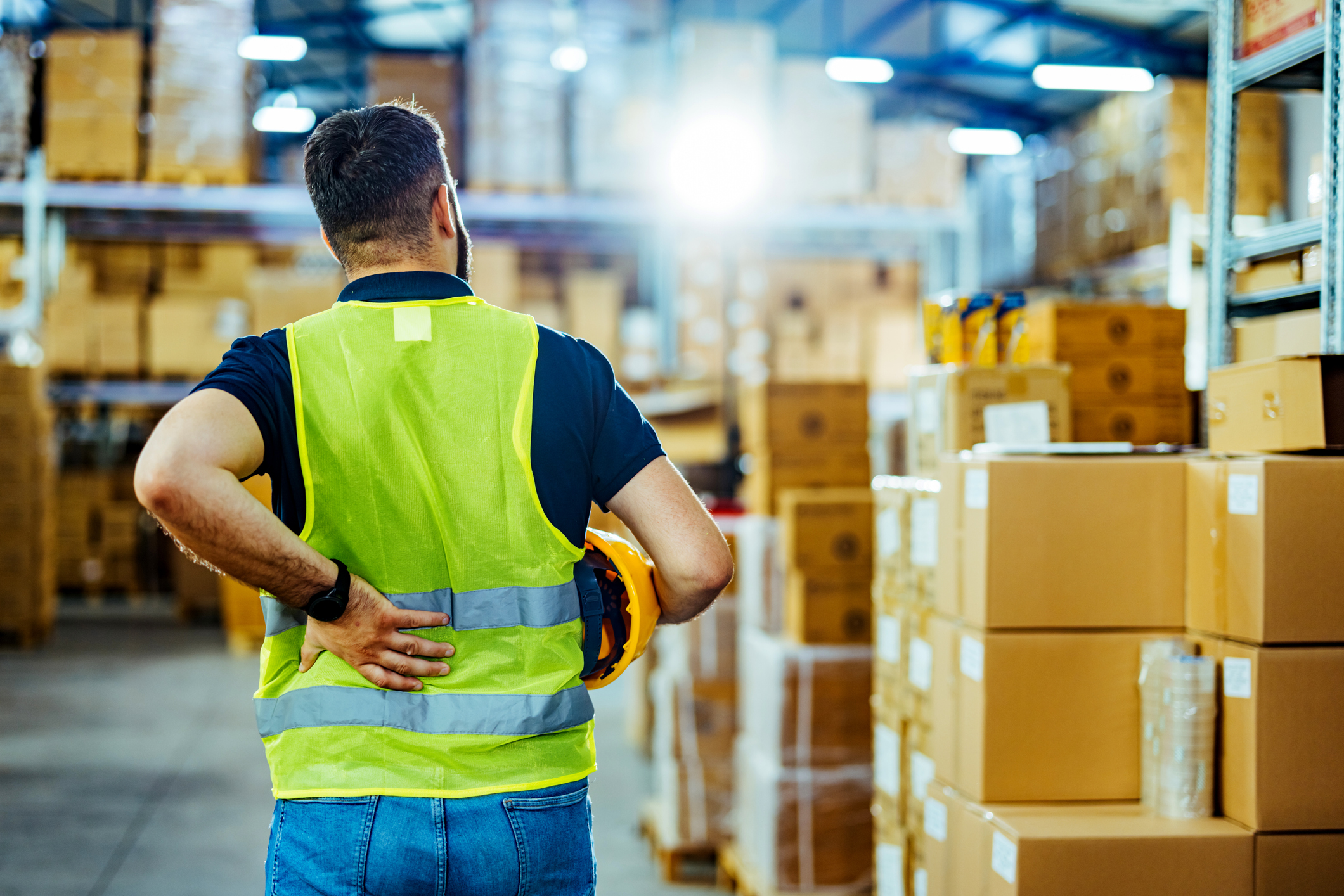 A-warehouse-worker-having-back-pain-and-rubbing-it.-1412175790