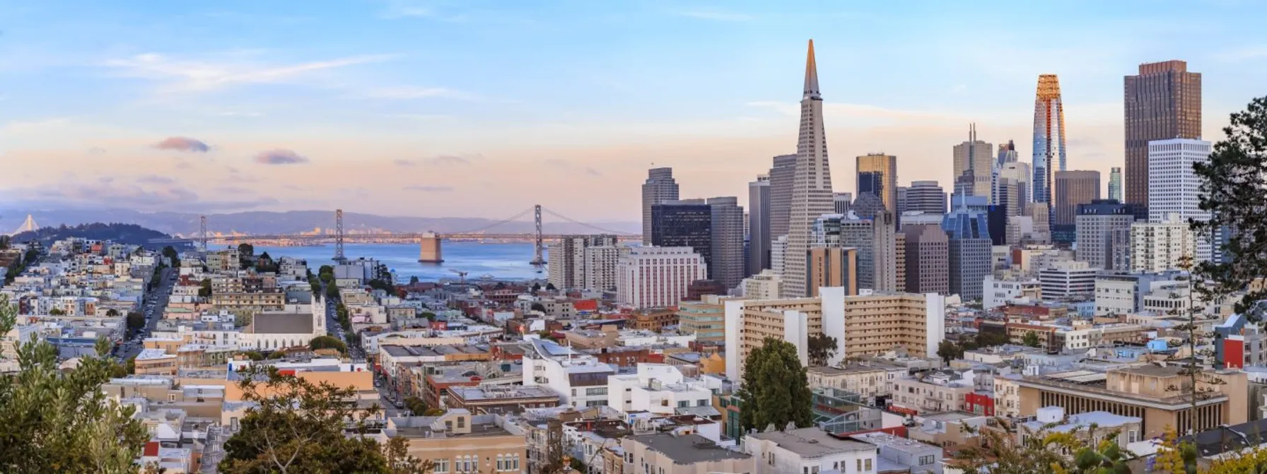 c137b482-san-francisco-skyline-panorama-at-sunset-with-bay-bridge-and-downtown-skyline-1212646618-1440x539-1