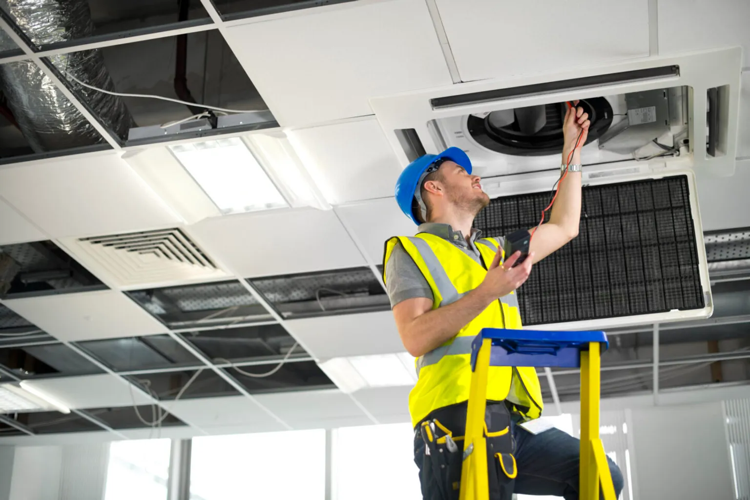 2dc8454e-electrician-fitting-air-conditioning-to-office-interior-476147011-1440x961-1