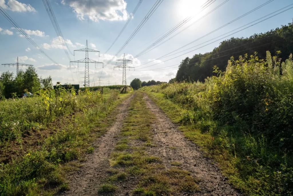 7f806177-dirt-road-in-the-landscape-on-a-sunny-day-with-high-voltage-power-lines-1367565329-1440x960-1