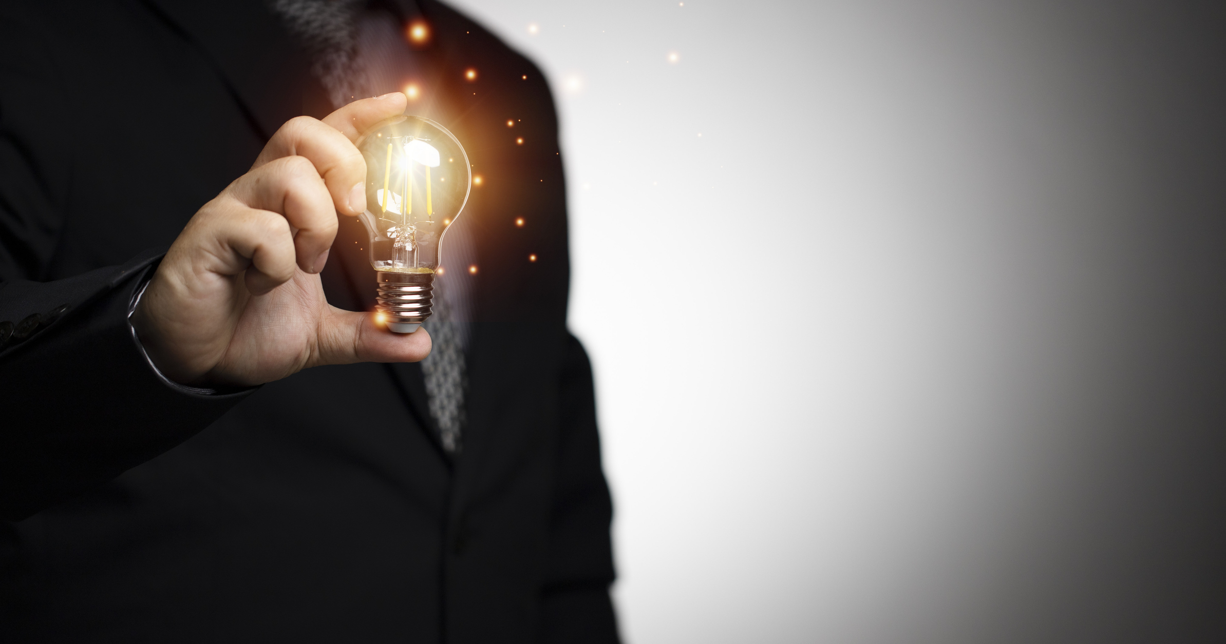 businessman holding a light bulb, there is a bright light Co