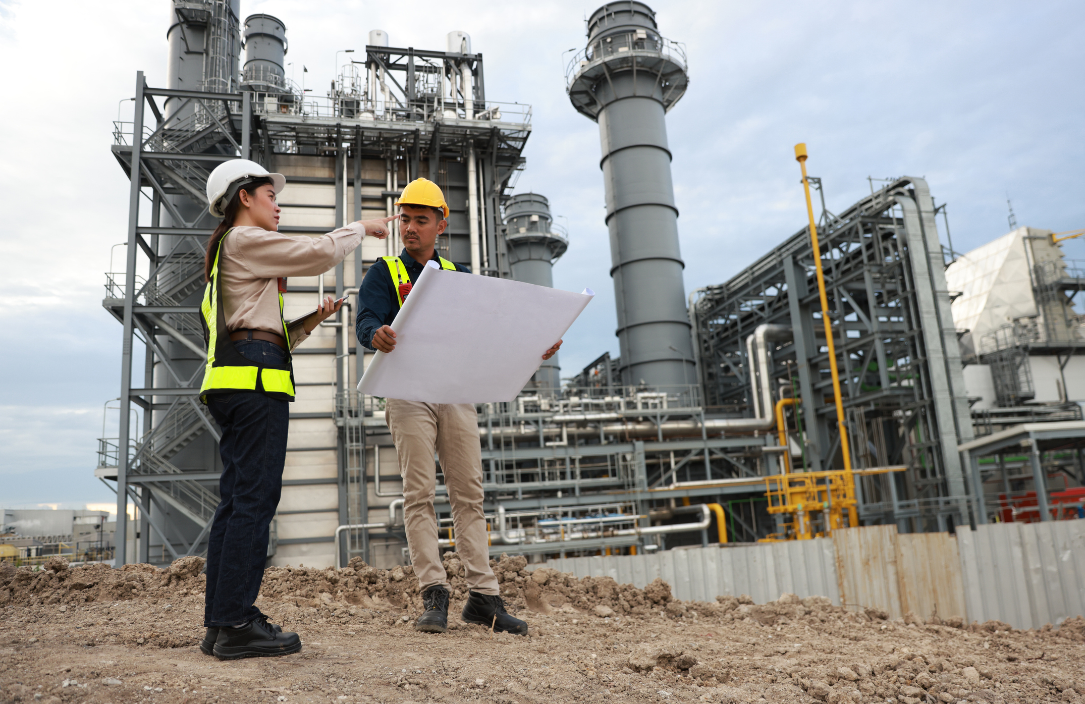 two project engineers Working with a blueprint and communica…