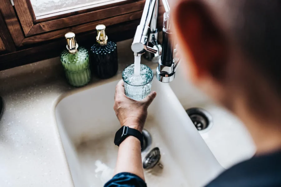 088350fb-man-filling-a-glass-of-filtered-water-right-from-the-tap-in-the-kitchen