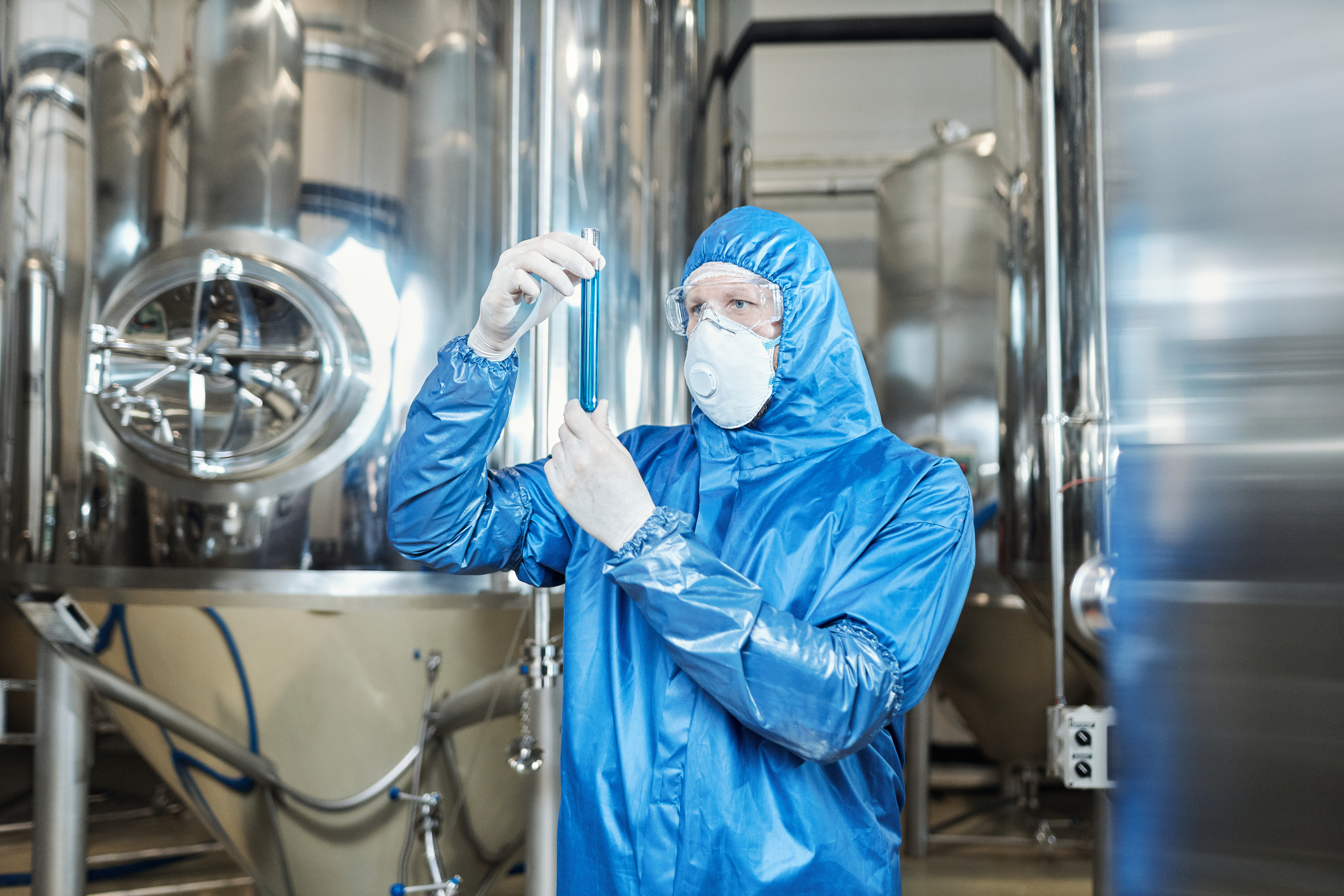 Worker wearing protective gear and holding test tube