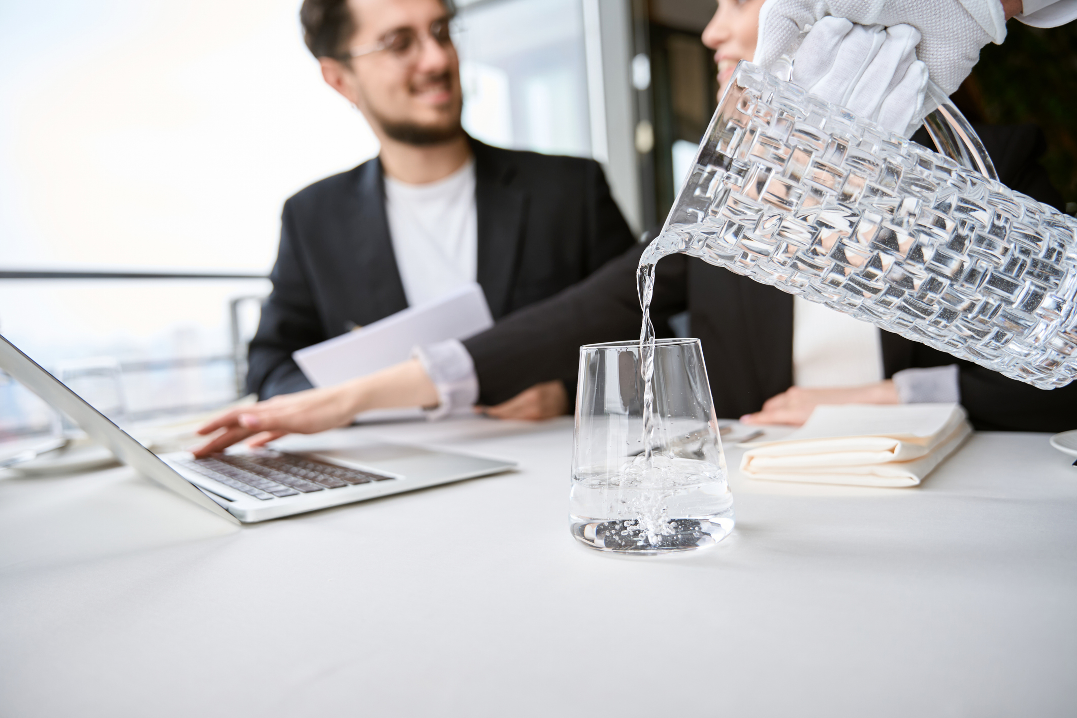 Waiter pouring water into a glass