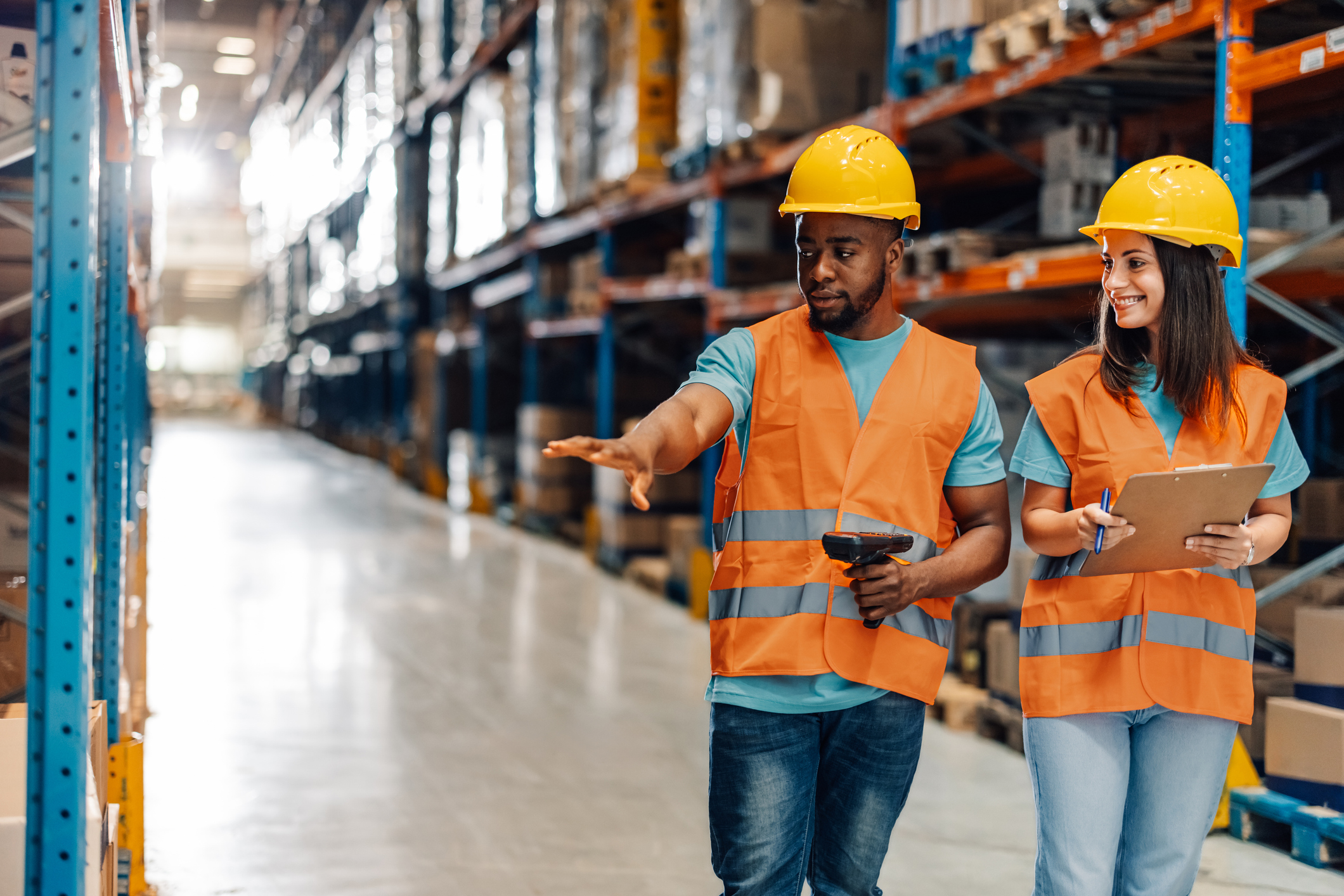 Diverse workers navigating warehouse aisle discussing