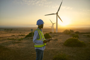 Wind turbine, field and engineering man with renewable energy for countryside, sustainability and farming technology. Clean energy, sustainable and electricity windmill of person on tablet in sunset