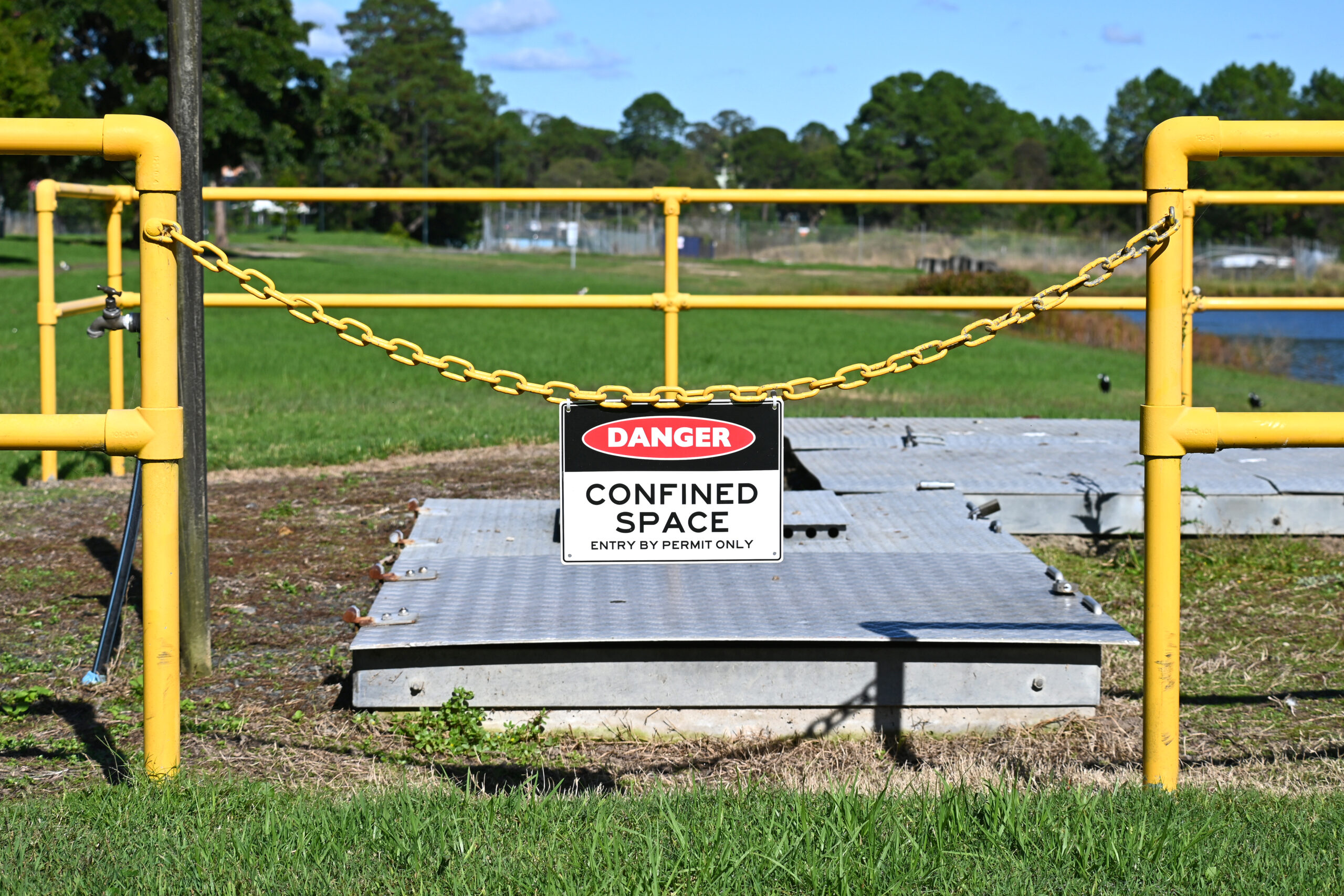 Danger confined space sign on a fence around a man hole