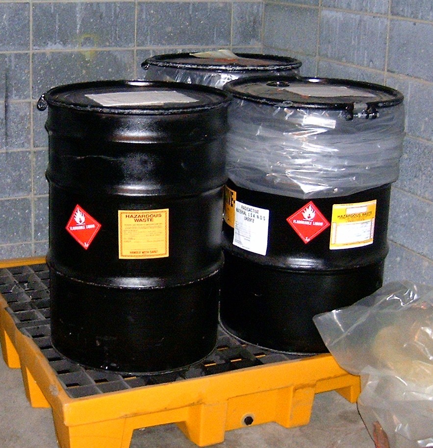 three drums with hazardous materials signage on them