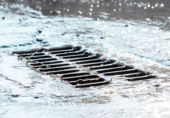 A storm grate overflowing with water