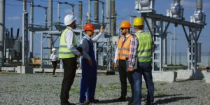 4 men in hard hats stand by a substation