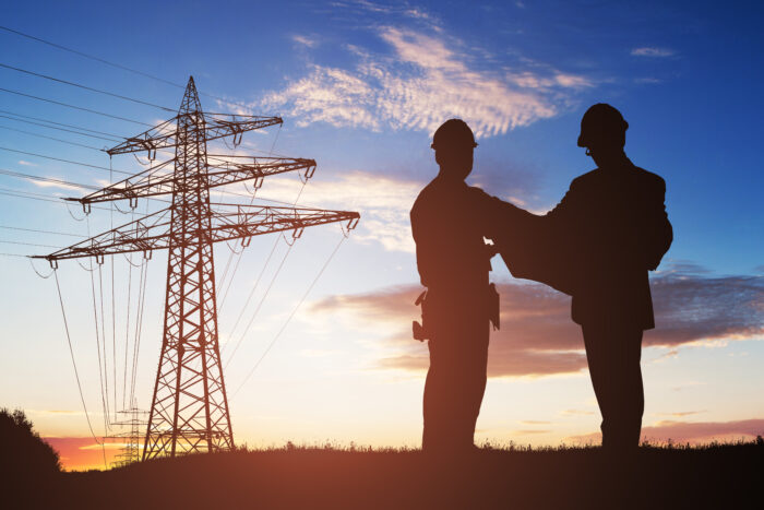 Silhouette-Of-Two-Engineers-Discussing-Together-921353782